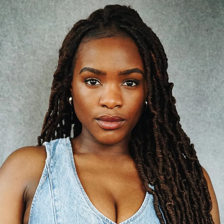 Vanessa Fisher, cast of One Day the Musical. Headshot with long locs, wearing a denim top.